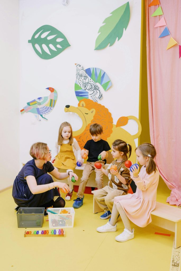 Farbenfrohes Vorschulklassenzimmer mit Lehrerin und Kindern, die mit Spielzeug spielen.