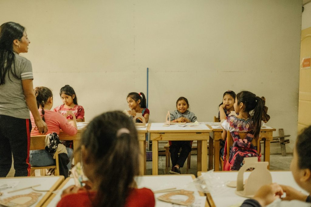 eine Gruppe von Kindern, die in einem Klassenzimmer an Schreibtischen sitzen